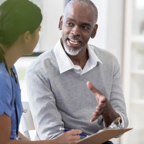 A man asks questions at his appointment with his doctor.