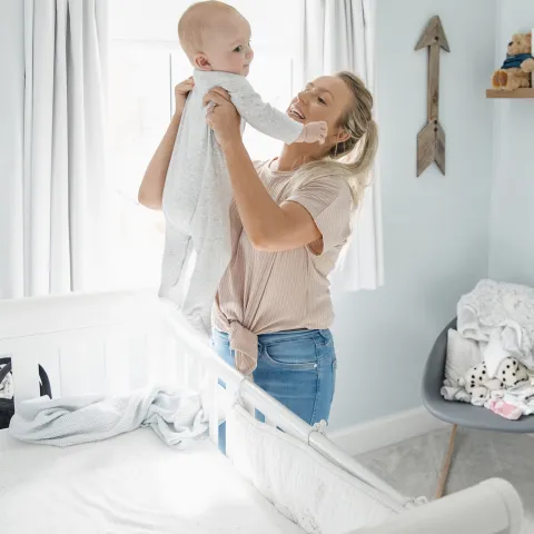 A mom lifts her infant out of the crib.