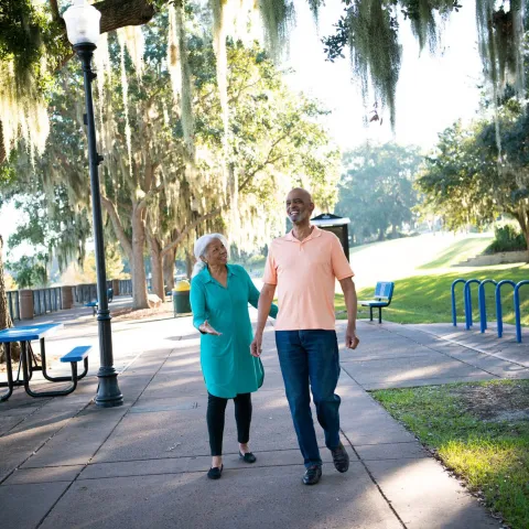 A Couple Walks Through a Park By a Lake in Clermont Florida, Laughing and Enjoying the Outdoors.