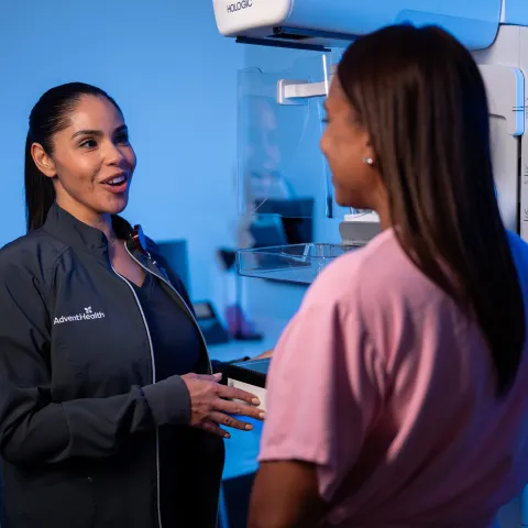 A imaging technician talking with a patient about to get a mammogram.
