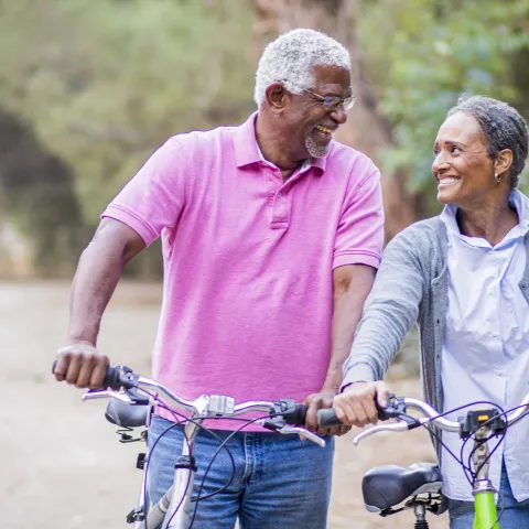 Older couple walking with bikes.