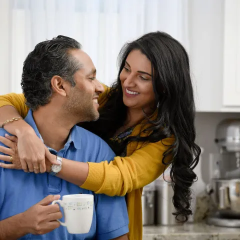 Happy couple embracing in the kitchen.