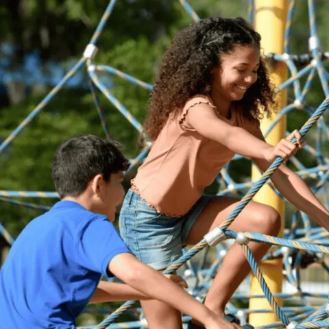 Two children climbing on a rope structure.