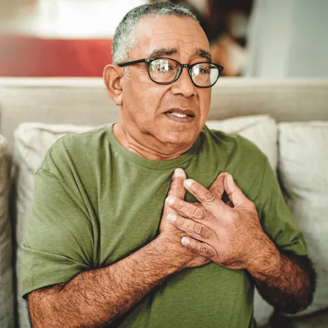 An older man holding his chest.