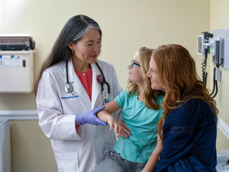 A Centra Care Physician Checks a Little Girl's Arm With Her Mom Watching