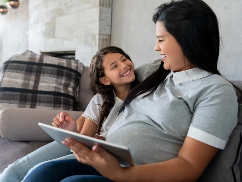 A pregnant mother and her daughter on the couch.