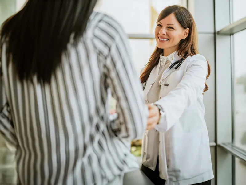 Smiling doctor reaching out to woman