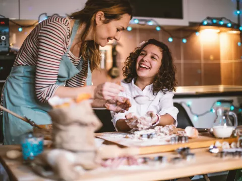 Mother and daughter baking Christmas cookies together in a kitchen.