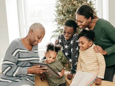 Family looking at photo album next to a Christmas tree
