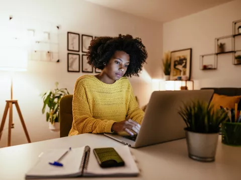 Woman looking at her laptop screen in a home office in the evening