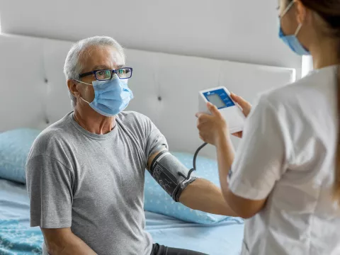 A home care nurse takes a patient's blood pressure.