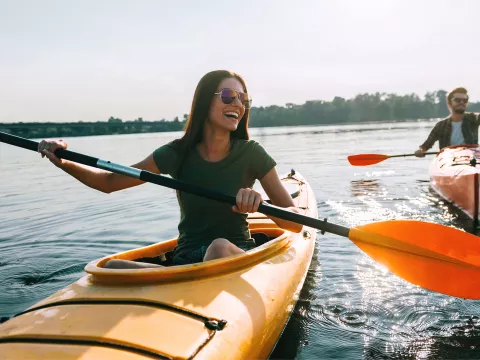 A Woman Kayaks With a Friend on a Lake 