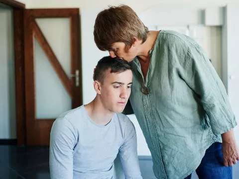 A Mother Comforts Her Son By Kissing Him on the Top of His Head.