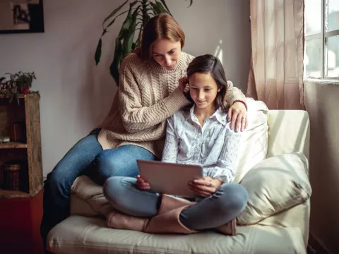 A mother and daughter reading from a tablet