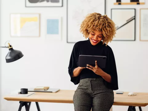 A slender, African American woman using a tablet at her office