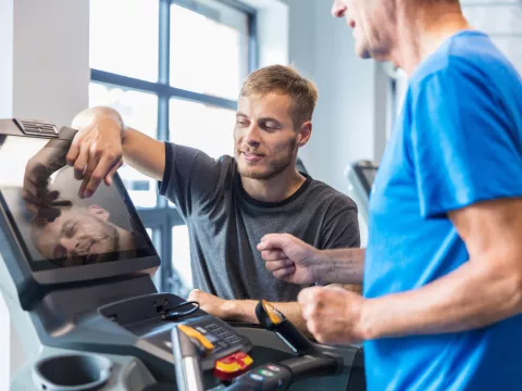 A Trainer Sets Up a Treadmill for a Patient