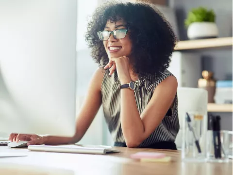 A Woman Smiles as She Reads on Her Computer at Home.
