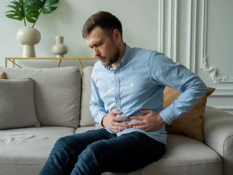 A Man Winces in Pain as He Hold's his Side