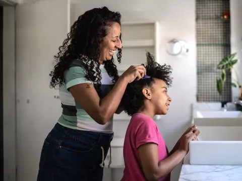A Mother Helps Her Daughter with Her Hair in The Bathroom.