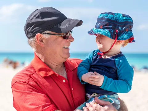 A Grandfather Holds His Grandson on the Beach