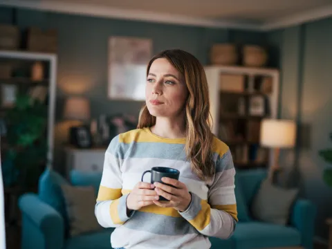 A Woman Looks Out Her Window While Drinking Coffee