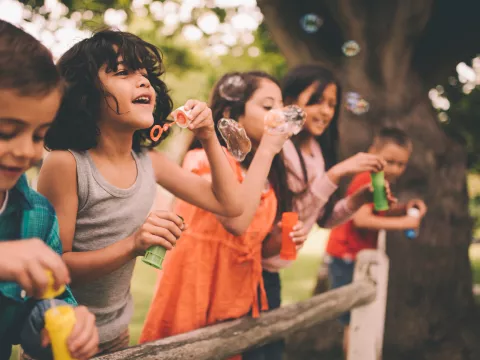 A group happy children blowing bubbles during the summer.