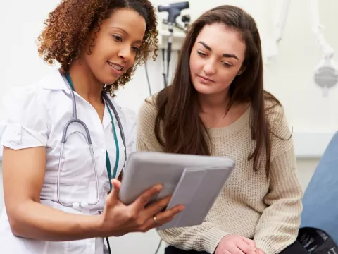 A nurse shows a young woman her test results from a prevenetive screening.