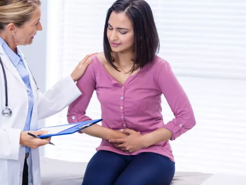 A woman experiencing stomach pain visits her doctor.