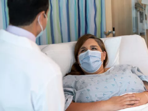 A doctor meeting with his patient while she lays in bed.