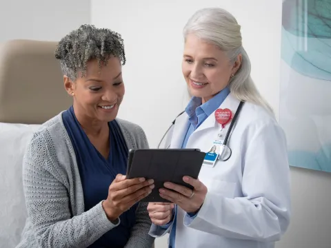 A woman and her female doctor look at information on a tablet.