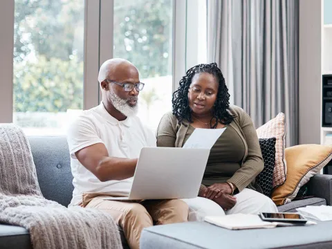 Man and woman reviewing paperwork with computer on lap