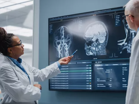 Two doctors discussing MRI scans of a head.