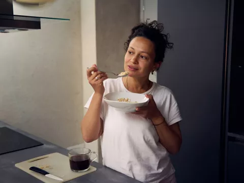 A hispanic woman eating a bowl of food.