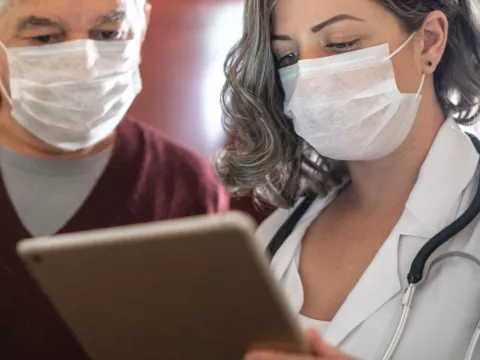 A doctor showing her patient something on her business tablet