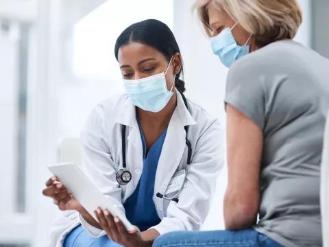 A physician showing something to her patient on her business tablet