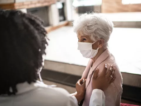 An elderly woman being comforted by her doctor