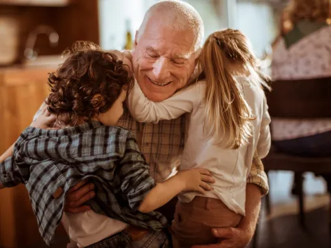 A grandfather hugs his grandchildren.
