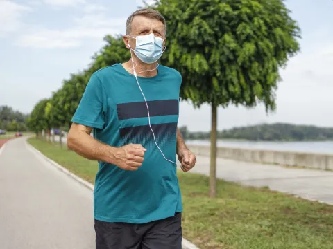 A man running outside wearing a mask.