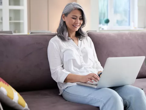 A woman using her computer while sitting on the couch.