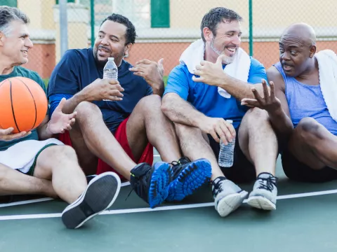A group of men resting on the sidelines during a game of basketball.