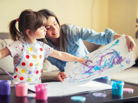 A mother and young daughter painting together. 