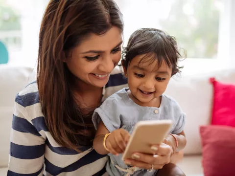 A mom uses her phone with her child.