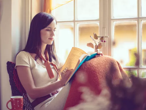 Woman reading near a window.