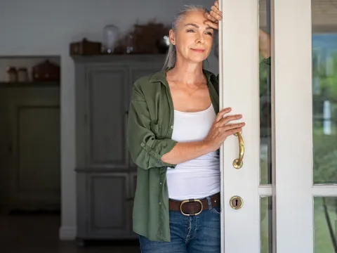 A woman standing by her doorway.