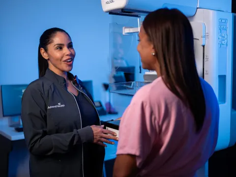 A imaging technician talking with a patient about to get a mammogram.