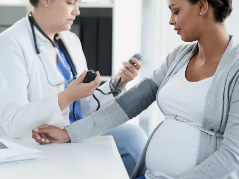One pregnant woman getting her blood checked by a female doctor in scrubs.