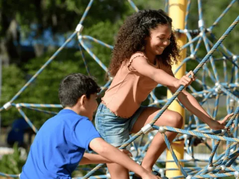 Two children climbing on a rope structure.