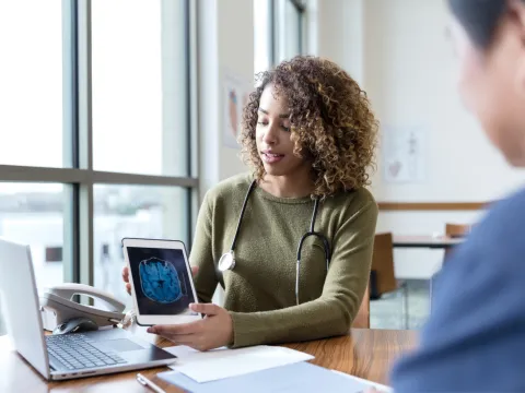 A patient and physician looking at a laptop screen