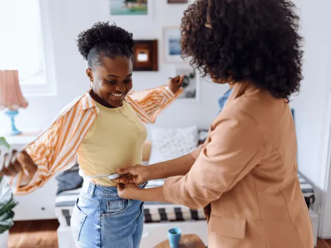 A woman measuring her daughter's waist.
