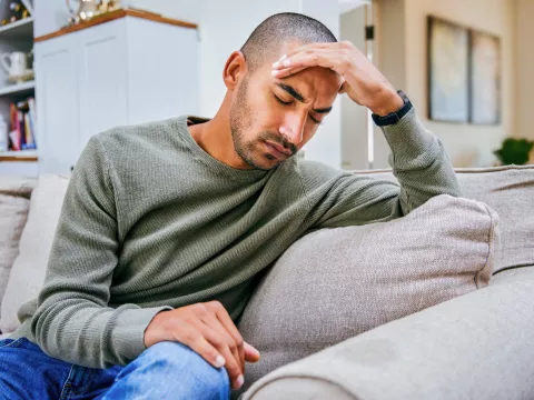 A young man holds his hand against his forehead.